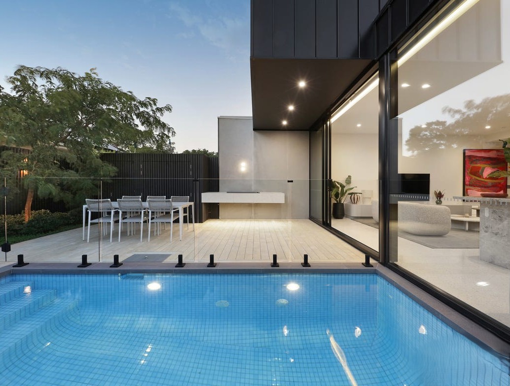 Custom home outdoor pool and living area at dusk